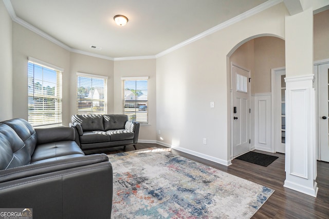 living room with decorative columns, crown molding, and dark wood-type flooring