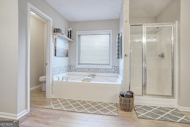 bathroom featuring toilet, hardwood / wood-style floors, and shower with separate bathtub