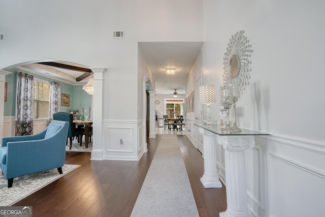 corridor with dark hardwood / wood-style flooring and ornate columns