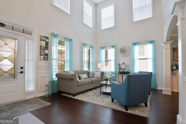 living room featuring ornate columns, a healthy amount of sunlight, and dark hardwood / wood-style floors