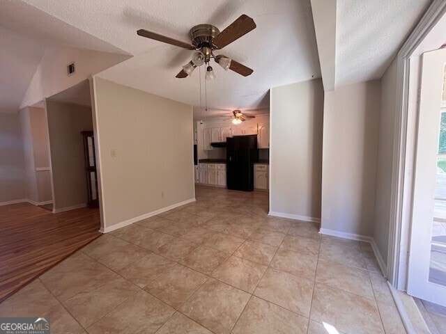 spare room featuring ceiling fan, light tile patterned flooring, a textured ceiling, and vaulted ceiling