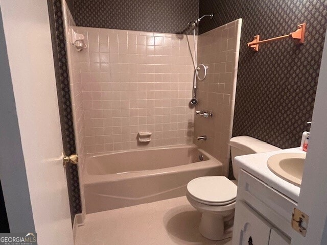 full bathroom featuring tiled shower / bath, vanity, and toilet