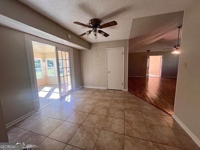 spare room with a textured ceiling, ceiling fan, light hardwood / wood-style floors, and vaulted ceiling