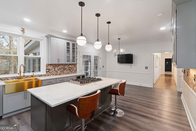 kitchen featuring sink, gray cabinets, a kitchen island, dark hardwood / wood-style flooring, and stainless steel gas cooktop