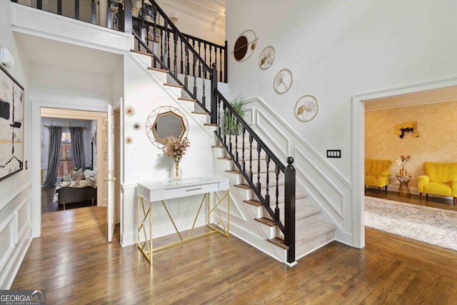 stairway with hardwood / wood-style floors, crown molding, and a high ceiling