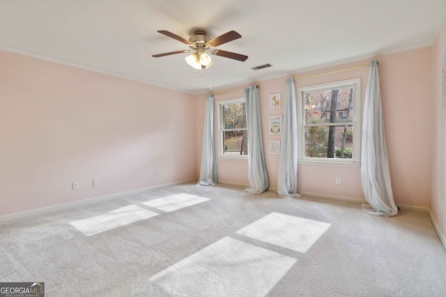 empty room featuring light colored carpet, ceiling fan, and ornamental molding