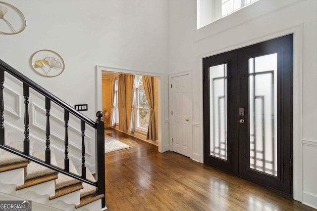 entryway with french doors, wood-type flooring, and a towering ceiling