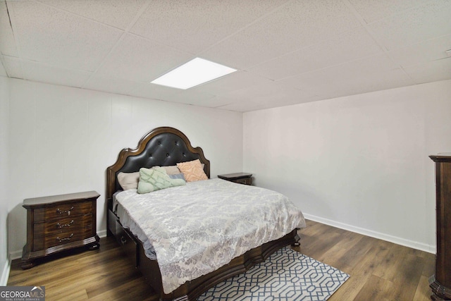 bedroom with a drop ceiling and dark wood-type flooring