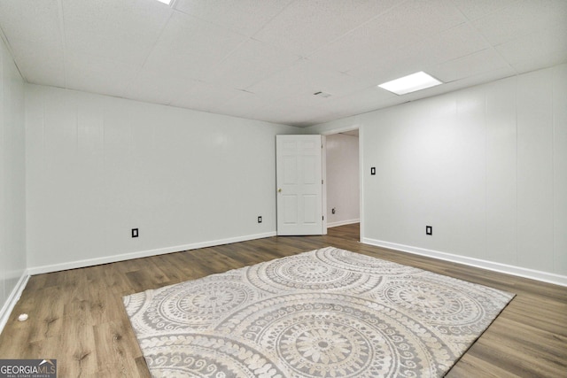 empty room with a drop ceiling and wood-type flooring