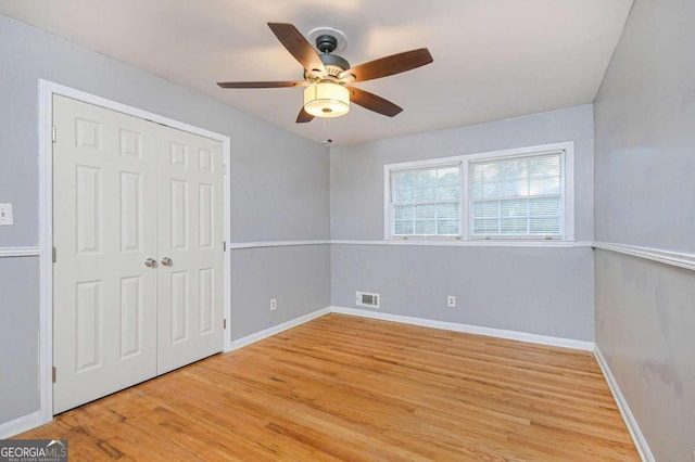 unfurnished bedroom featuring hardwood / wood-style floors, ceiling fan, and a closet