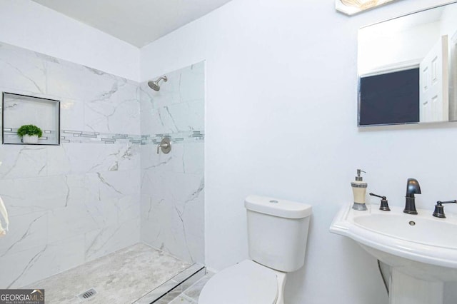 bathroom with tiled shower, sink, and toilet