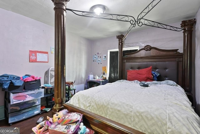 bedroom with decorative columns and hardwood / wood-style flooring