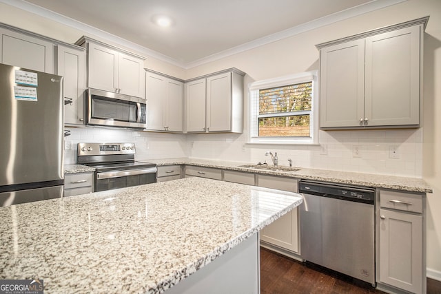 kitchen featuring sink, dark hardwood / wood-style floors, ornamental molding, appliances with stainless steel finishes, and light stone counters