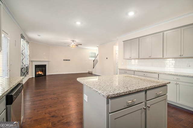 kitchen with gray cabinetry, a center island, dark wood-type flooring, stainless steel dishwasher, and ornamental molding