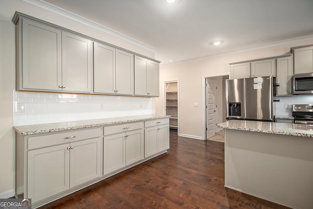 kitchen featuring light stone countertops, dark hardwood / wood-style flooring, stainless steel appliances, and tasteful backsplash