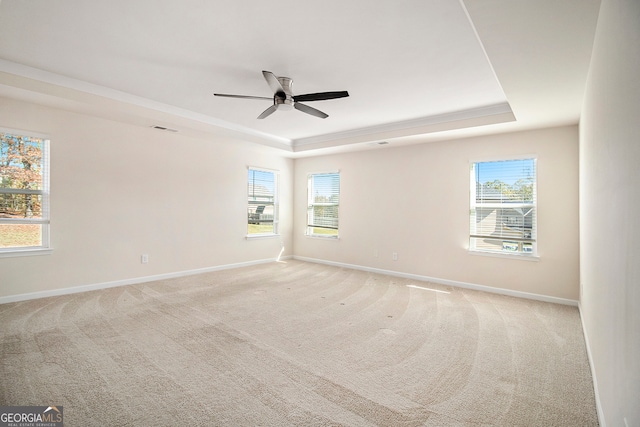 unfurnished room with ceiling fan, light carpet, and a tray ceiling