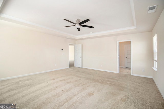 unfurnished room featuring light colored carpet, a raised ceiling, and ceiling fan