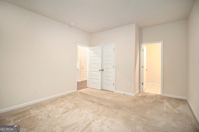 unfurnished bedroom featuring light carpet and a closet