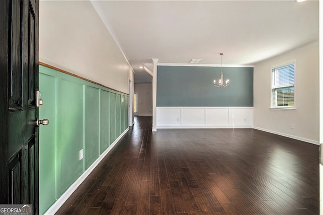 spare room with dark hardwood / wood-style flooring, crown molding, and an inviting chandelier