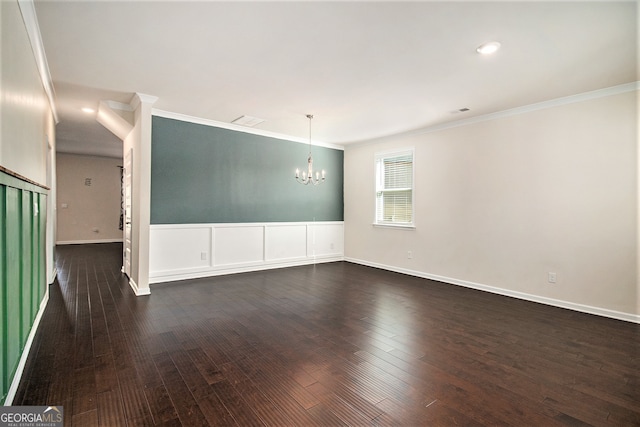 spare room featuring crown molding, dark wood-type flooring, and a notable chandelier