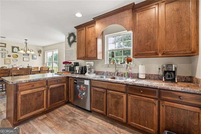 kitchen featuring an inviting chandelier, hardwood / wood-style flooring, stainless steel dishwasher, and a healthy amount of sunlight