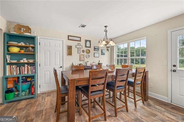 dining area with dark hardwood / wood-style flooring and a chandelier