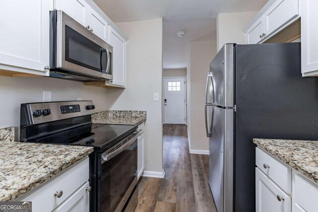 kitchen featuring white cabinets, dark hardwood / wood-style flooring, stainless steel appliances, and light stone countertops