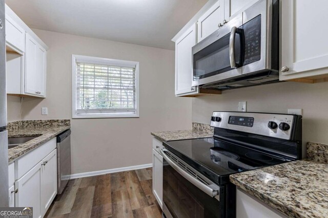 kitchen with white cabinetry, dark wood-type flooring, light stone counters, and appliances with stainless steel finishes