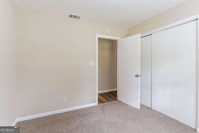 unfurnished bedroom with light colored carpet and a closet