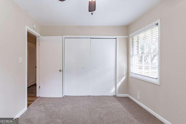 unfurnished bedroom featuring ceiling fan, a closet, and carpet floors