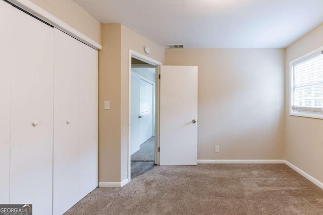 unfurnished bedroom with light colored carpet and a closet