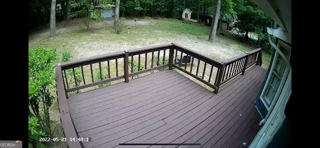 wooden deck with a storage unit and a lawn