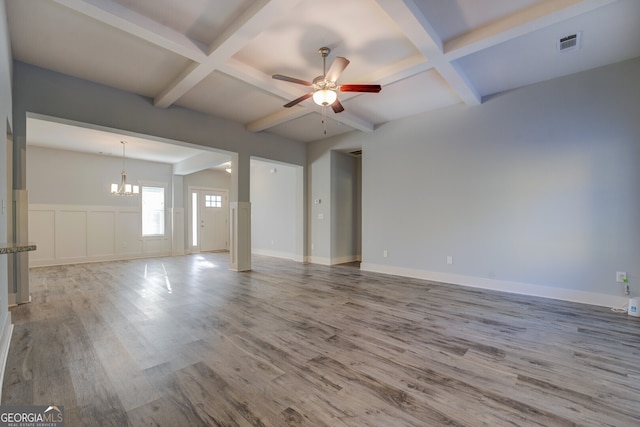 empty room with hardwood / wood-style floors, ceiling fan with notable chandelier, coffered ceiling, and beam ceiling