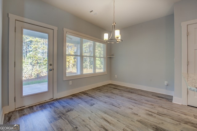 unfurnished dining area with hardwood / wood-style flooring and an inviting chandelier