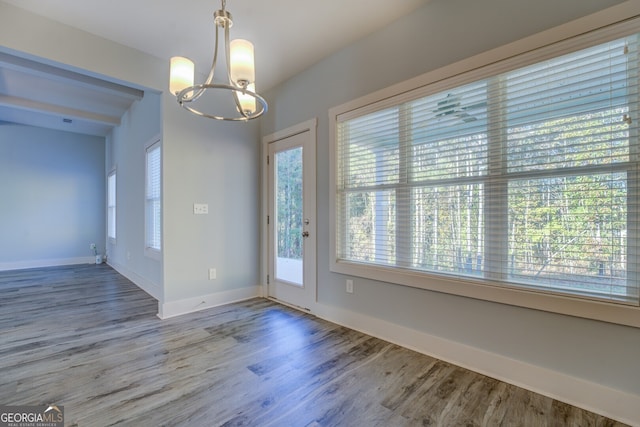 unfurnished dining area with a notable chandelier and hardwood / wood-style flooring