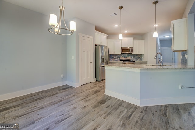 kitchen with hanging light fixtures, sink, light hardwood / wood-style flooring, appliances with stainless steel finishes, and white cabinetry