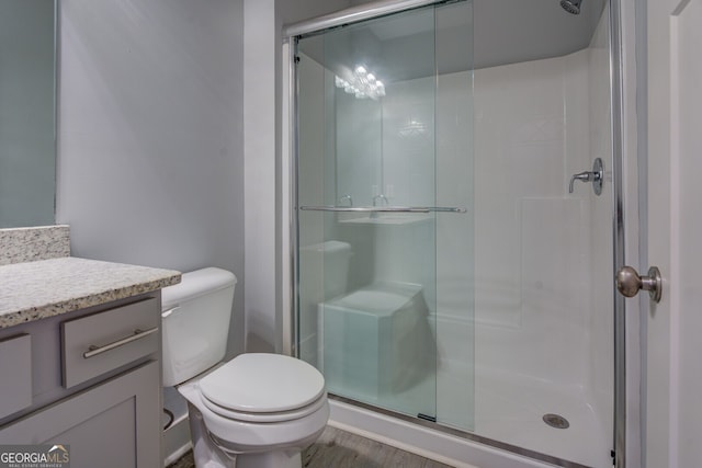 bathroom with hardwood / wood-style flooring, vanity, toilet, and a shower with door