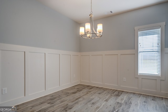 unfurnished dining area featuring a chandelier and light wood-type flooring