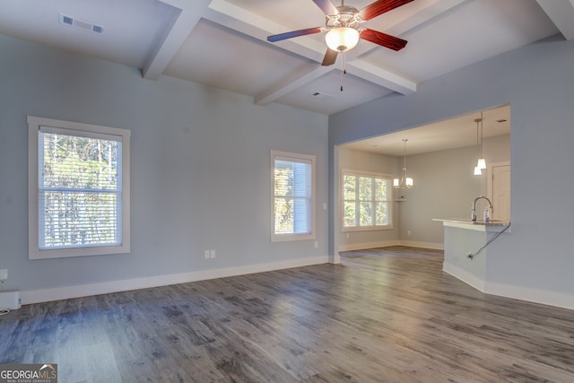 unfurnished living room with beamed ceiling, a healthy amount of sunlight, and dark wood-type flooring