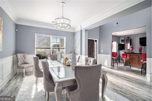 dining space featuring a chandelier, ornamental molding, and light hardwood / wood-style flooring