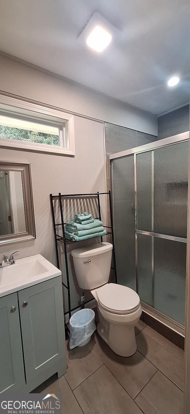 bathroom with tile patterned floors, vanity, toilet, and walk in shower