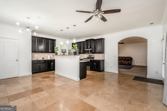 kitchen featuring hanging light fixtures, appliances with stainless steel finishes, decorative backsplash, a kitchen island, and ornamental molding