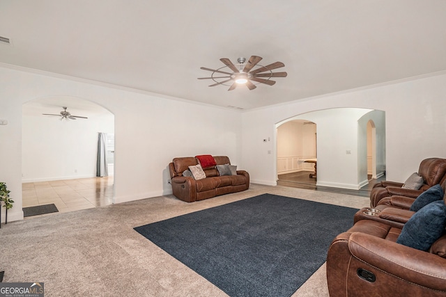 living room with ceiling fan, ornamental molding, and light carpet