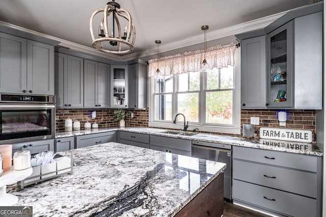 kitchen featuring light stone counters, gray cabinetry, stainless steel appliances, sink, and decorative light fixtures