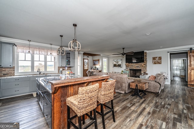 kitchen featuring a center island, gray cabinets, a stone fireplace, and backsplash