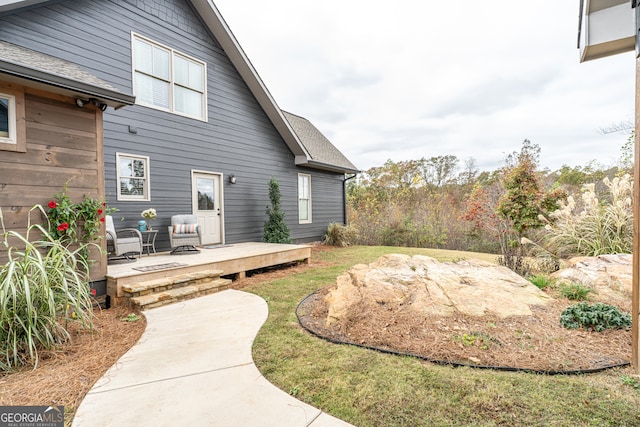 rear view of property featuring a wooden deck and a patio area