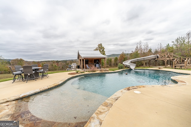 view of pool featuring a diving board, a patio area, and a water slide