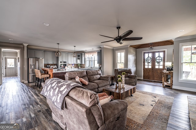 living room with french doors, ornamental molding, ceiling fan, dark wood-type flooring, and sink