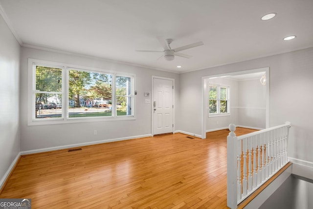 empty room with light wood-type flooring, plenty of natural light, crown molding, and ceiling fan