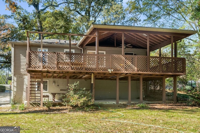 back of property featuring ceiling fan, a lawn, and a wooden deck